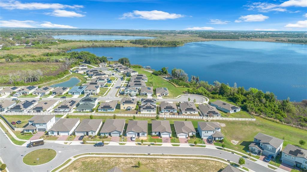 An aerial view shows a suburban neighborhood with houses situated along a large lake — 3224 WEITZEL DRIVE, HAINES CITY, FL