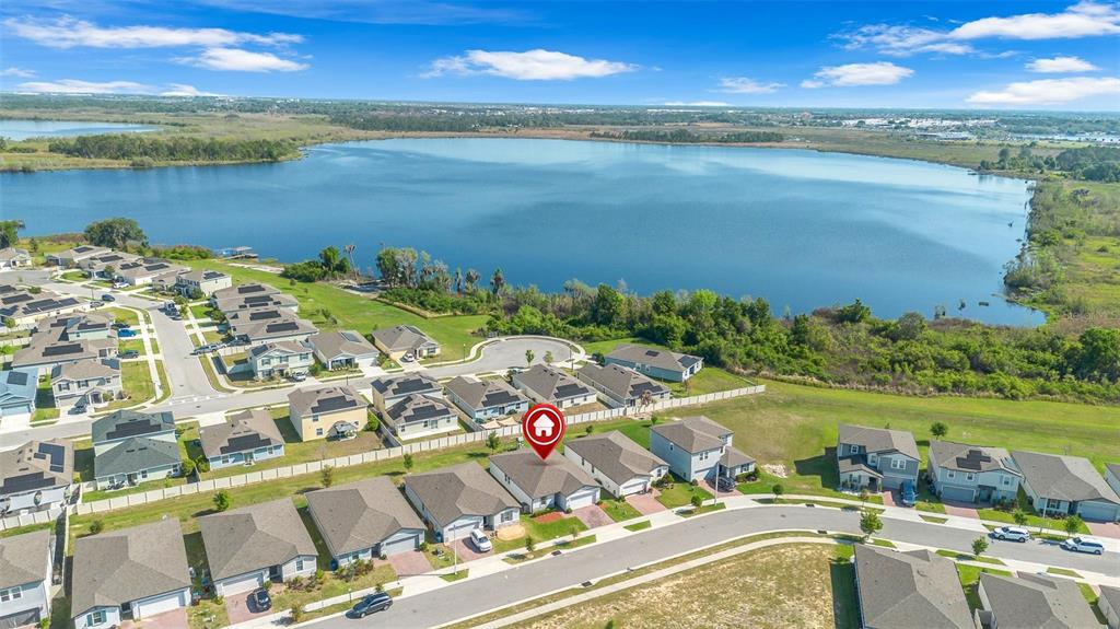An aerial view shows a suburban neighborhood with houses situated near a large lake — 3224 WEITZEL DRIVE, HAINES CITY, FL
