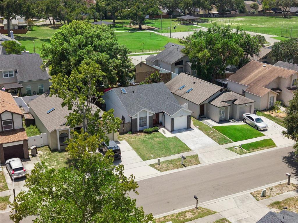 An aerial view shows a suburban street with several single-family homes and a grassy park — 1256 PIN OAK DRIVE, APOPKA, FL