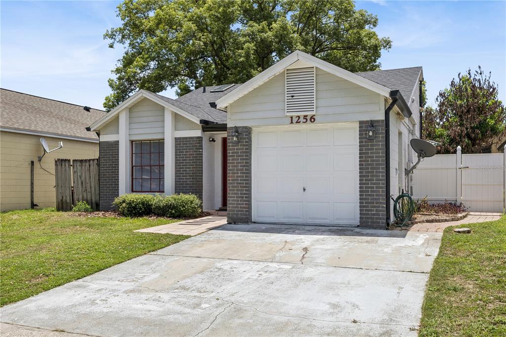 A single-story house with a white garage, gray brick accents, and a concrete driveway — 1256 PIN OAK DRIVE, APOPKA, FL