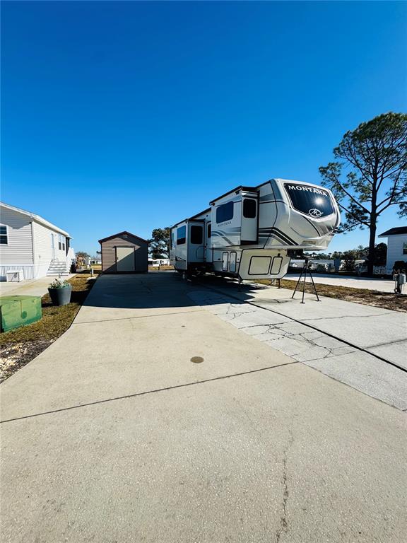 A large Montana fifth-wheel RV is parked on a concrete driveway next to a shed — 328 ST GEORGE DRIVE, DAVENPORT, FL
