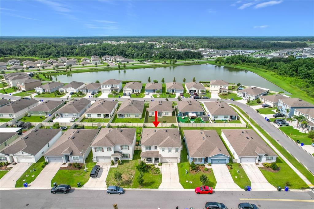 An aerial view shows a suburban neighborhood with houses, a lake, and a red arrow — 5911 SHINGLE CREEK ROAD, LAKELAND, FL