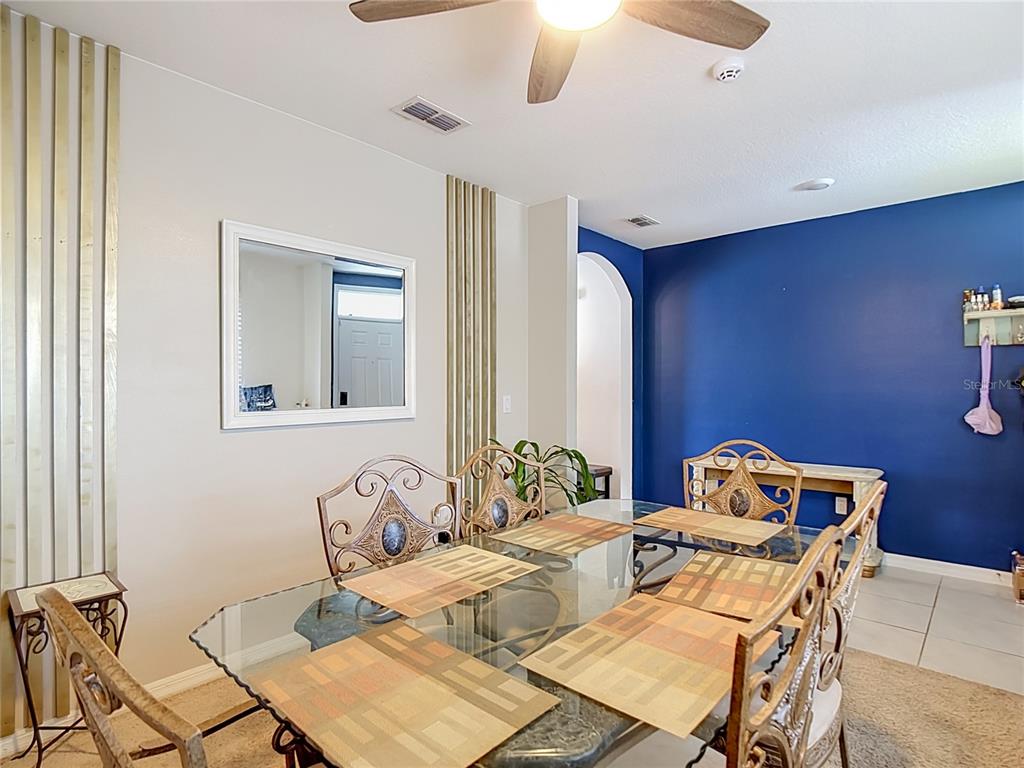A dining room features a glass-topped table with metal chairs, a mirror, and a blue wall — 5911 SHINGLE CREEK ROAD, LAKELAND, FL