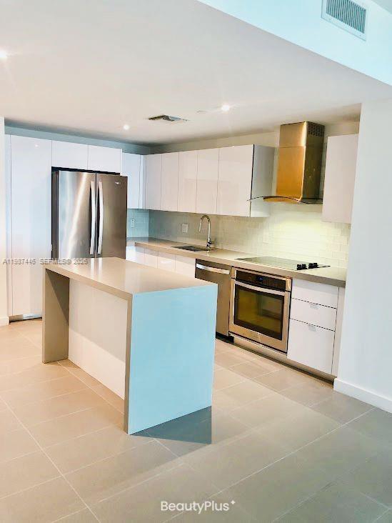 A modern kitchen features white flat-panel cabinets, stainless steel appliances, and a central island — 1600 NE 1st Ave # 1715, Miami FL 33132, MIAMI, FL