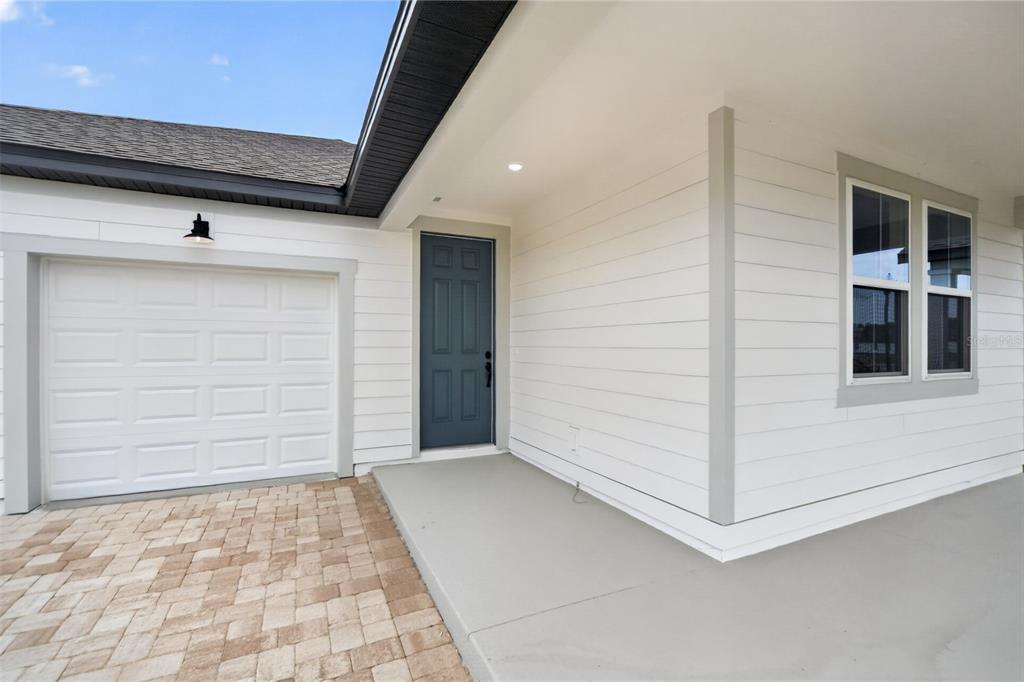 A white house exterior features a gray front door, a garage, and a paved driveway — 30157 MISTY PINES ROAD, MOUNT DORA, FL