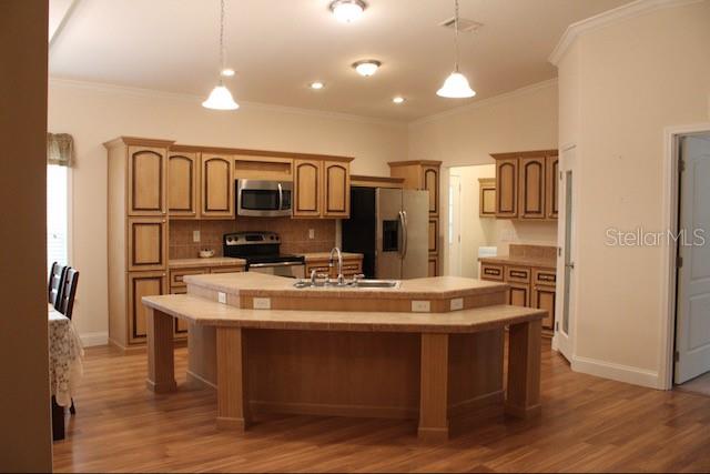 A kitchen features light wood cabinets, a tiled island with a sink, and hardwood floors — 1759 NE 127TH STREET, BRANFORD, FL