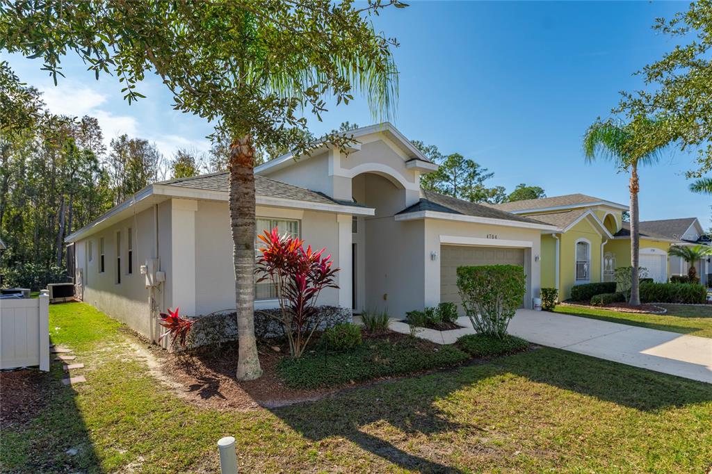 A single-story suburban house with a beige stucco exterior, a garage, and palm trees — 4704 BLUE DIAMOND STREET, KISSIMMEE, FL