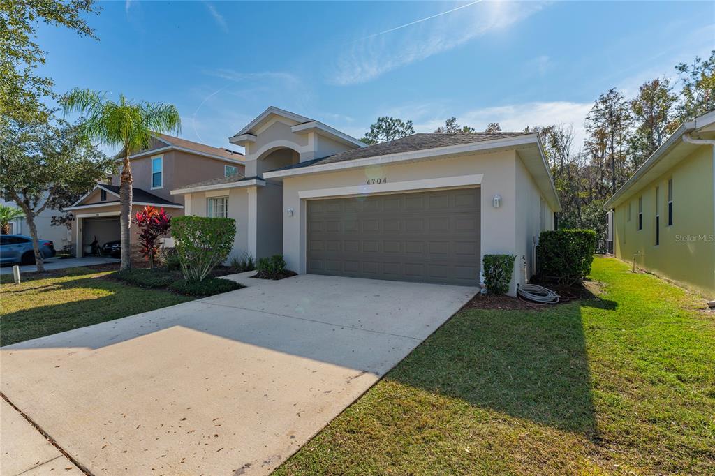 A single-story suburban house with a beige stucco exterior and a two-car garage — 4704 BLUE DIAMOND STREET, KISSIMMEE, FL