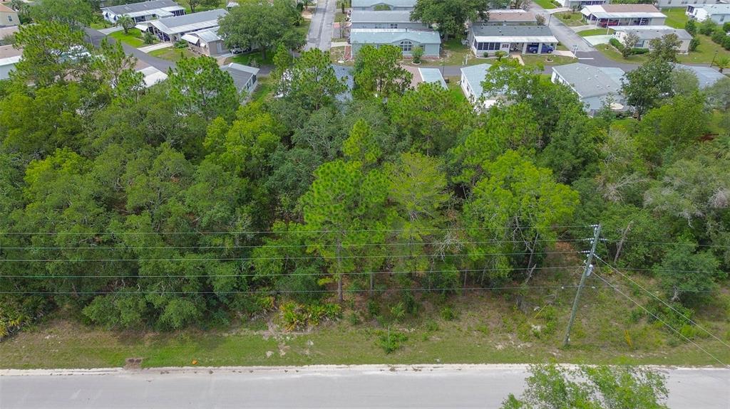 An aerial view shows a wooded, undeveloped rectangular lot situated between a road and houses — 6859 W MERRIVALE LANE, HOMOSASSA, FL