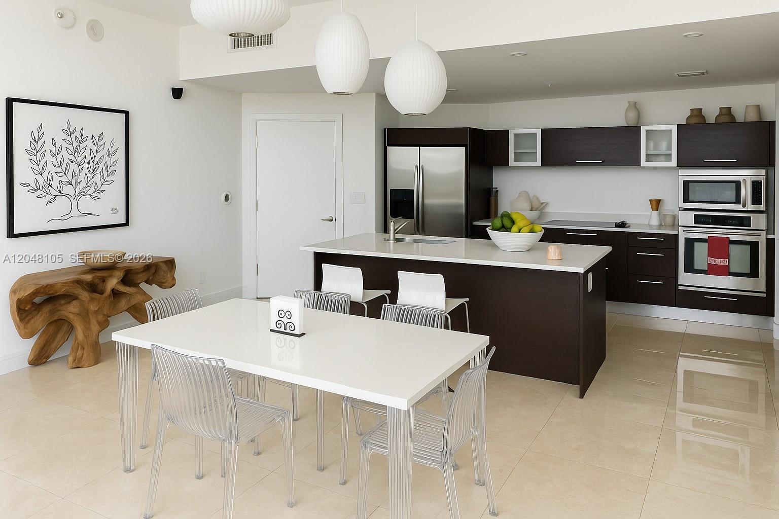 A modern kitchen and dining area feature dark wood cabinetry, white countertops, and clear chairs — 1900 N Bayshore Dr # 5003, Miami FL 33132, MIAMI, FL