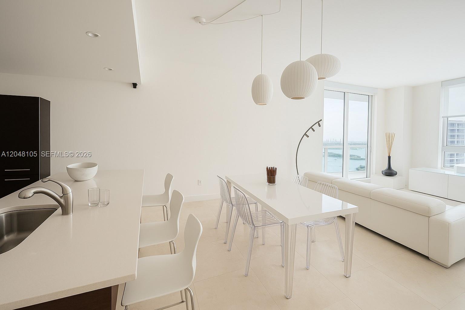 A modern, white-toned open-concept dining and kitchen area features a dining table and island — 1900 N Bayshore Dr # 5003, Miami FL 33132, MIAMI, FL