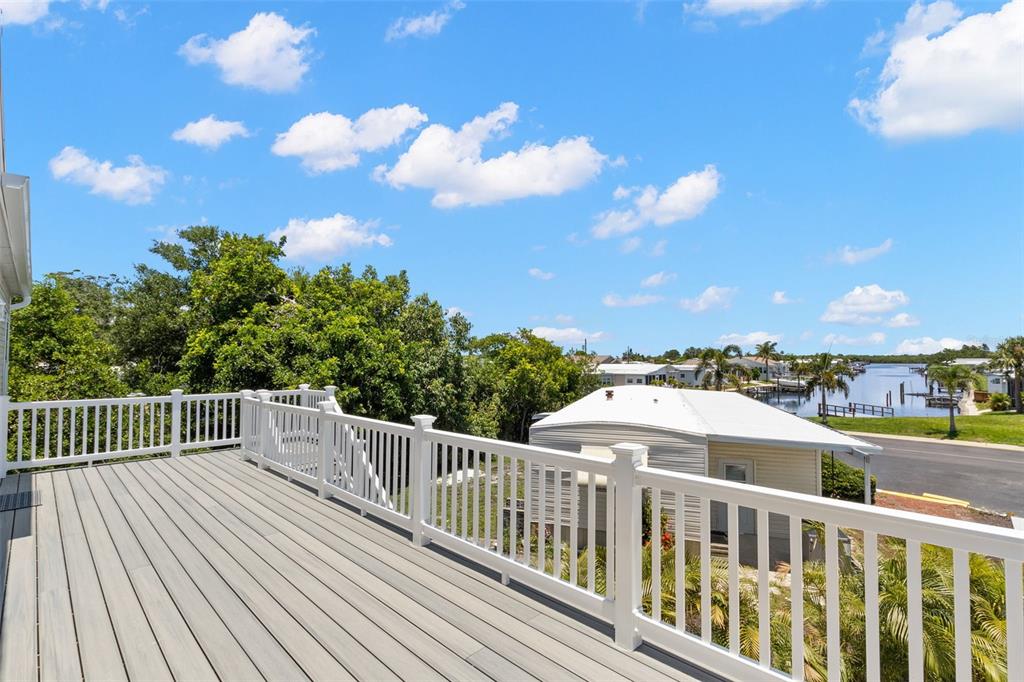 A spacious elevated deck with white railings overlooks a neighborhood and a nearby waterway — 6924 AMERICANA DRIVE NE UNIT 167, ST PETERSBURG, FL