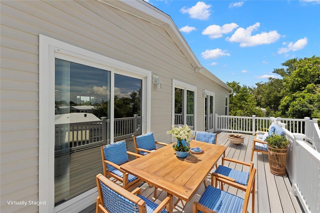 A wooden dining set sits on a deck with light-colored siding and white railings — 6924 AMERICANA DRIVE NE UNIT 167, ST PETERSBURG, FL