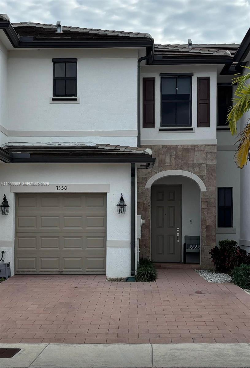 The exterior of a two-story townhouse features a garage, stone accents, and a front entrance — 3350 W 112th St, Hialeah FL 33018, HIALEAH, FL