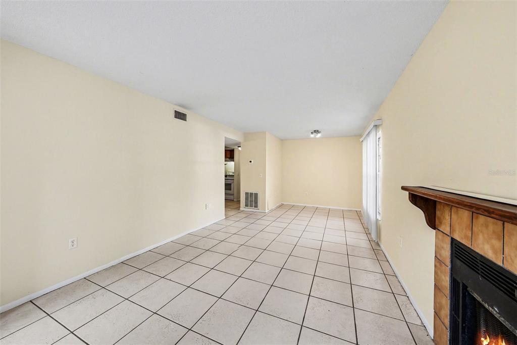 A living room with light-colored tile flooring, cream walls, and a tiled fireplace — 14319 HANGING MOSS CIRCLE UNIT 101, TAMPA, FL