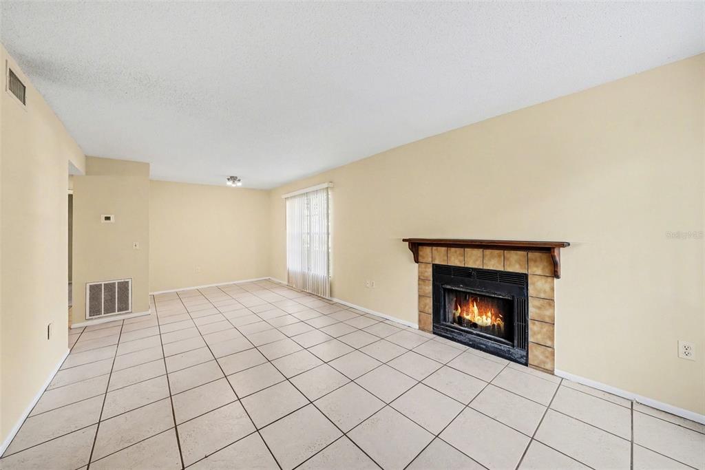 A living room features beige walls, light-colored tile flooring, and a fireplace with tile surround — 14319 HANGING MOSS CIRCLE UNIT 101, TAMPA, FL