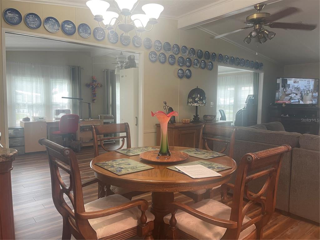 A dining area features a round wooden table, four chairs, and walls decorated with plates — 112 LYONIA LANE, WILDWOOD, FL