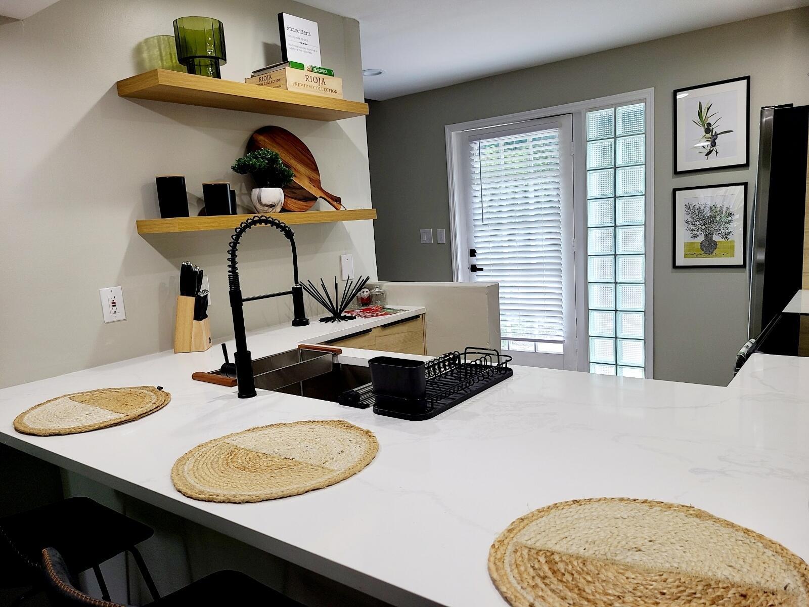 A kitchen island with a sink and woven placemats sits before open wood shelving — 690 SE 23rd Avenue # 1, Pompano Beach FL 33062, POMPANO BEACH, FL