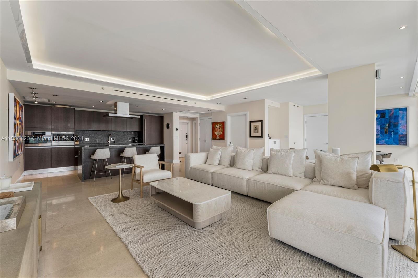 An open-concept living room features a modern kitchen with dark cabinetry and a sectional sofa — 101 Ocean Dr # 907, Miami Beach FL 33139, MIAMI BEACH, FL