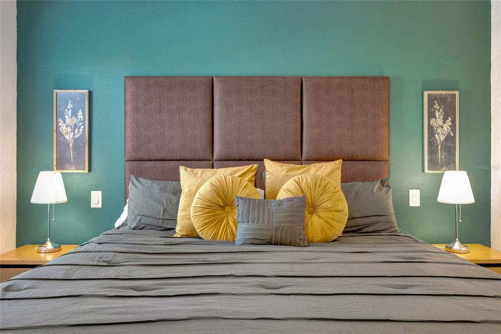 A bedroom features a brown upholstered headboard against a teal wall with two bedside lamps — 3050 WHITE ORCHID ROAD, KISSIMMEE, FL
