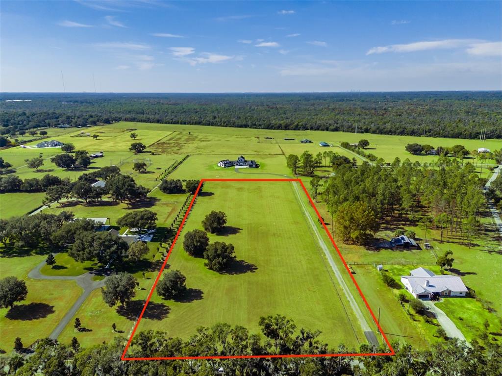 An aerial view shows a large, rectangular grassy lot outlined in red — 3527 POWERLINE ROAD, LITHIA, FL