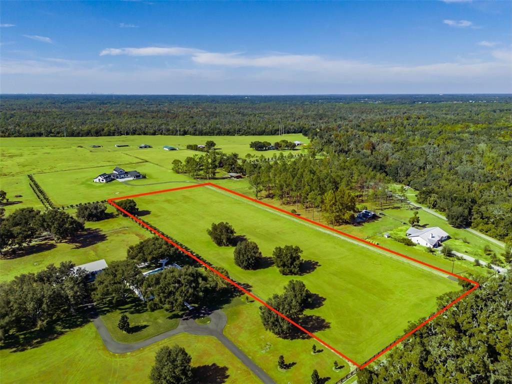 An aerial view shows a large, rectangular grassy lot outlined in red with scattered trees — 3527 POWERLINE ROAD, LITHIA, FL