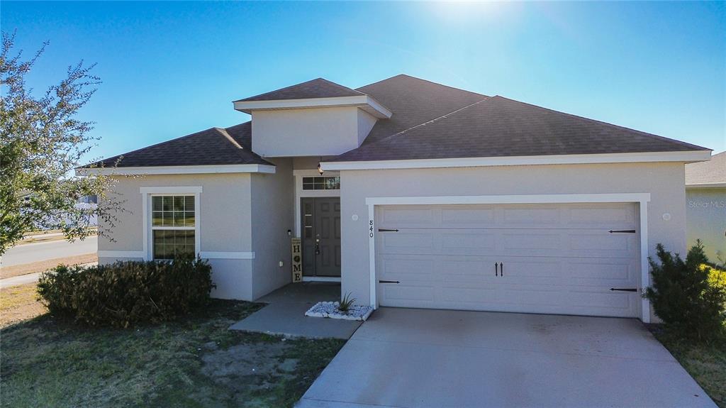 A single-story house with a beige stucco exterior, a two-car garage, and a front entrance — 840 SYDNEY STREET, DAVENPORT, FL