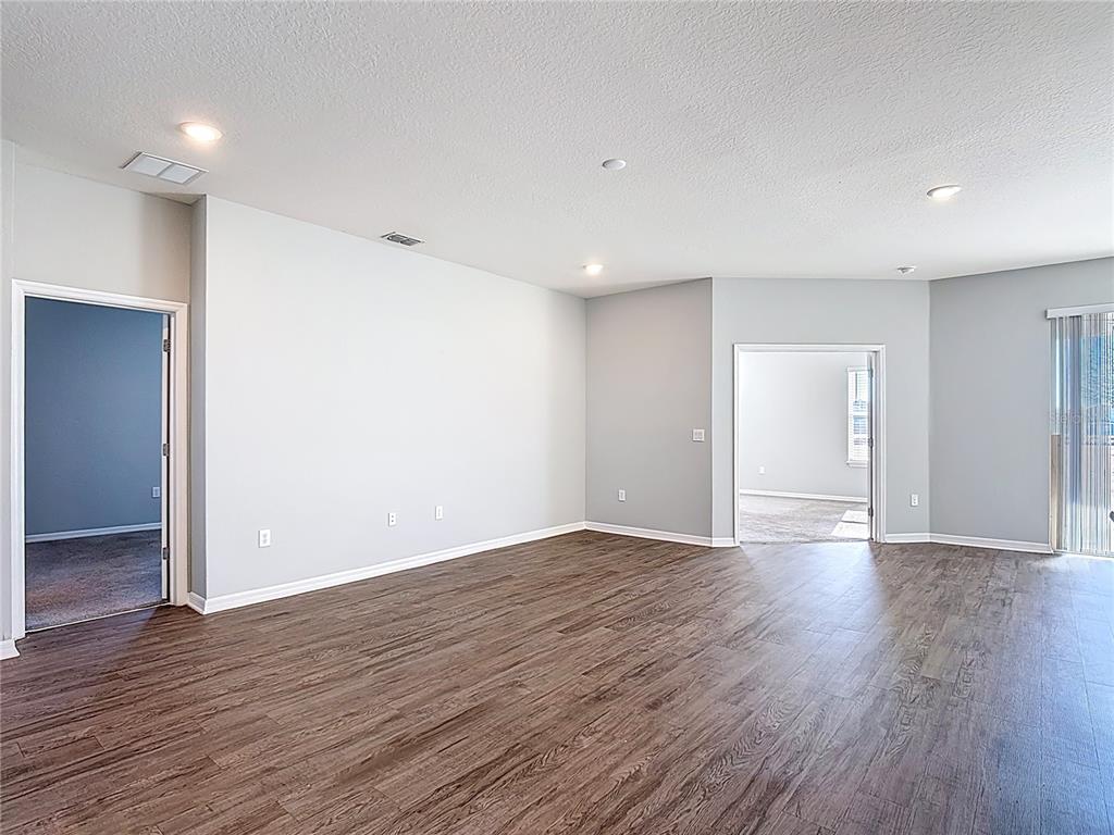 An empty room features light gray walls, dark wood-look flooring, and recessed ceiling lighting — 840 SYDNEY STREET, DAVENPORT, FL