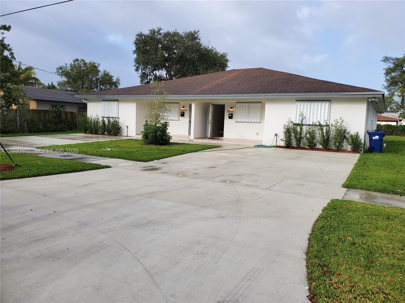 A single-story duplex with a large concrete driveway and white exterior walls — 10372 NW 10th Ave # 10372, Miami FL 33150, MIAMI, FL