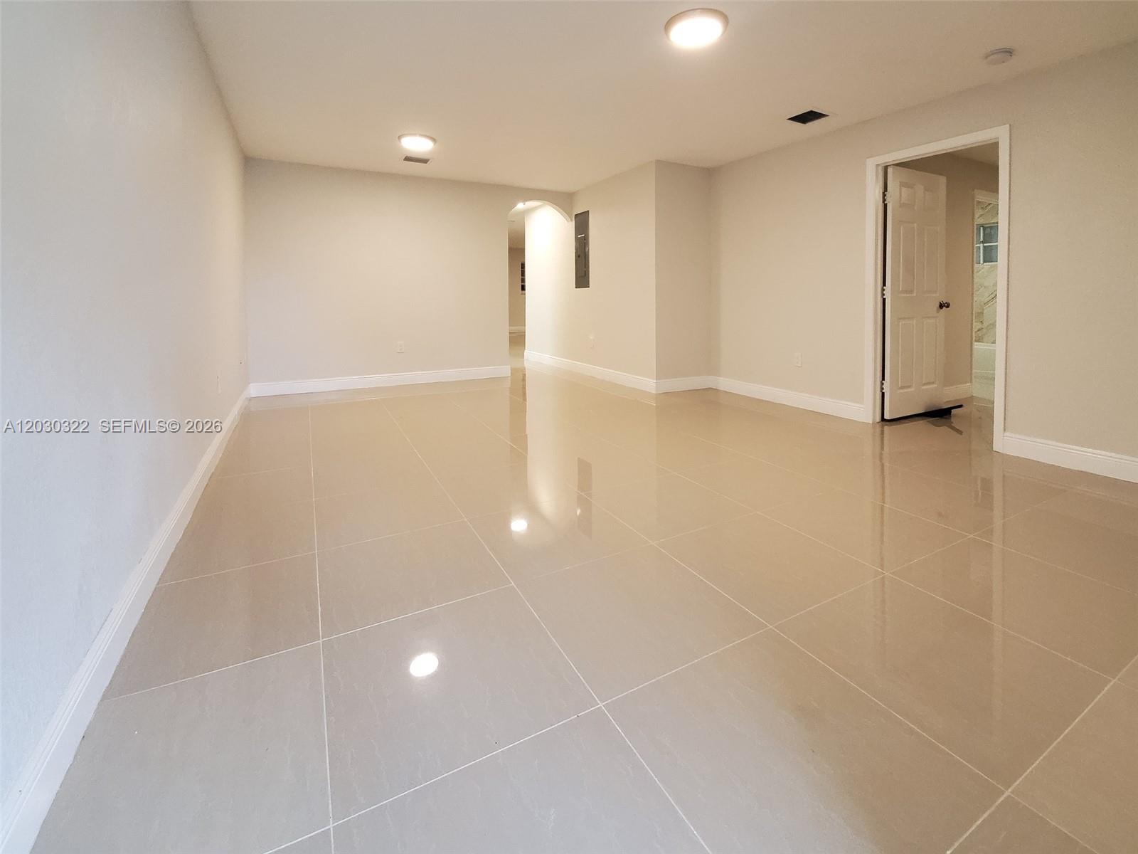 A spacious, empty room features light-colored tile flooring, recessed lighting, and a doorway leading elsewhere — 10372 NW 10th Ave # 10372, Miami FL 33150, MIAMI, FL