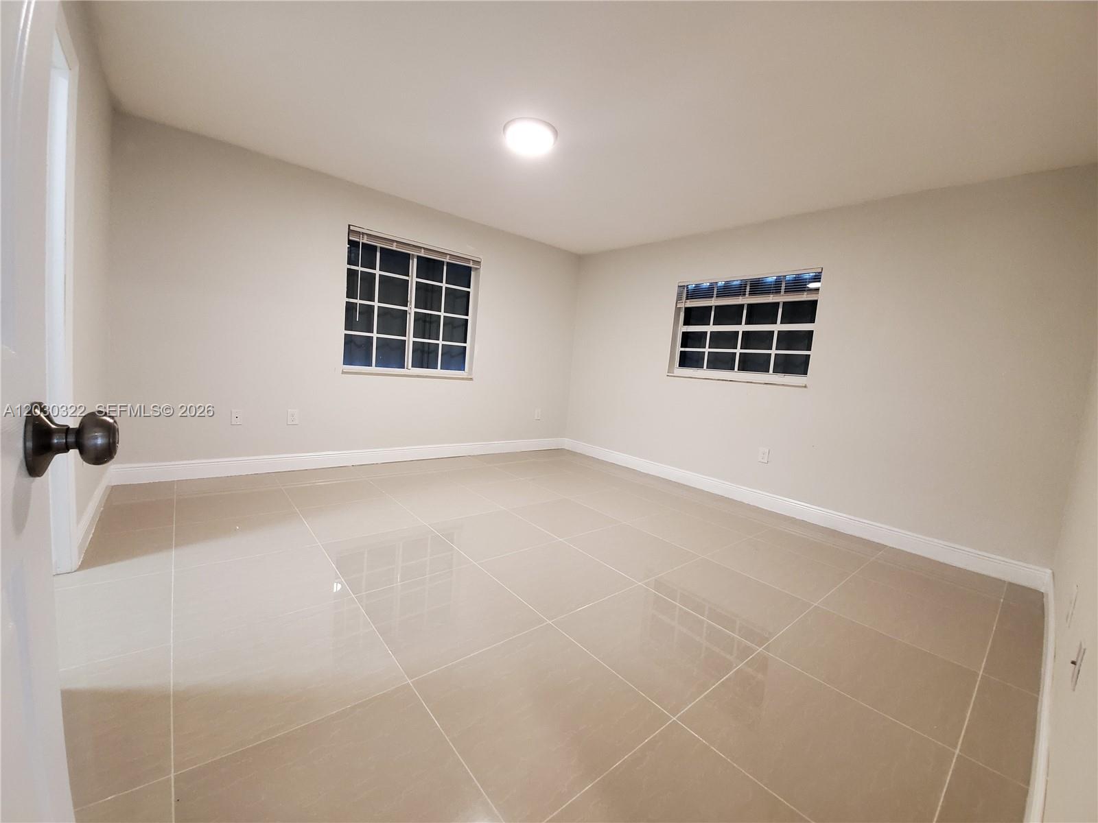 An empty room features light-colored tile flooring, white walls, and two windows with blinds — 10372 NW 10th Ave # 10372, Miami FL 33150, MIAMI, FL