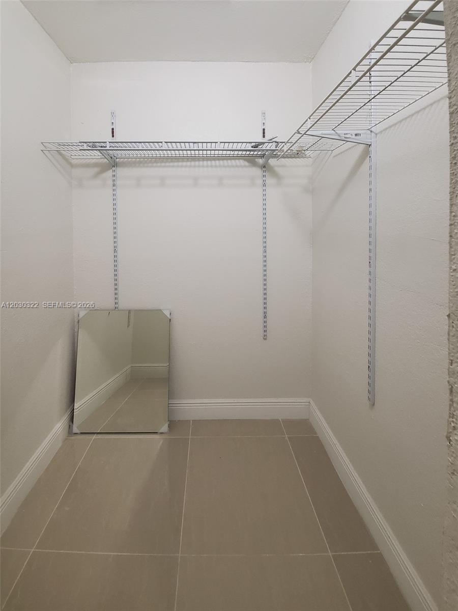 A walk-in closet features white walls, tile flooring, and wire shelving mounted on wall tracks — 10372 NW 10th Ave # 10372, Miami FL 33150, MIAMI, FL