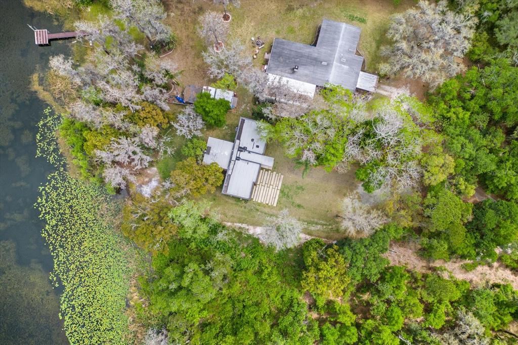 An aerial view shows two houses nestled in a wooded area next to a lake — 3807 S SEMORAN BOULEVARD, ORLANDO, FL