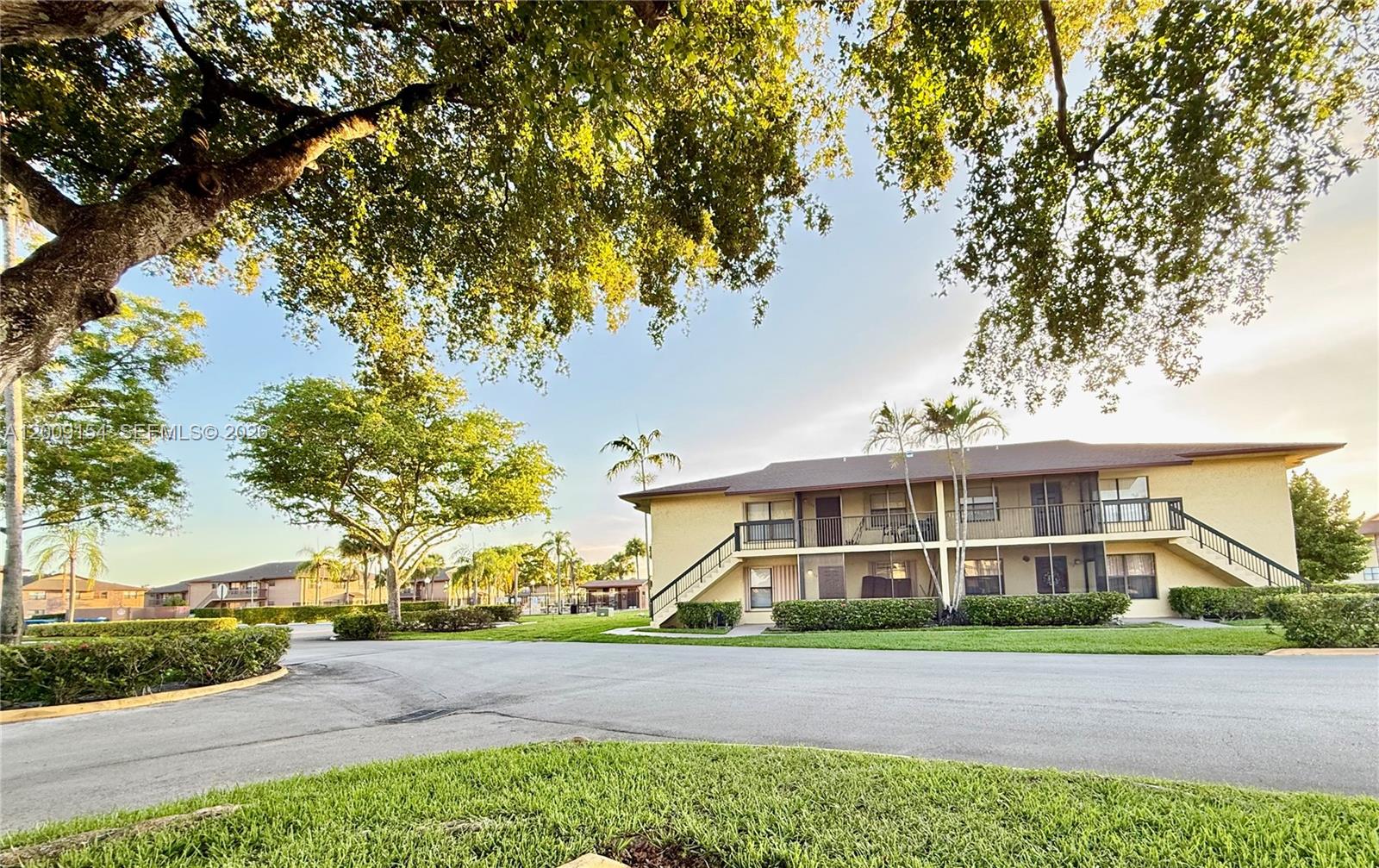 A two-story apartment building with exterior staircases sits behind a paved driveway and lawn — 10016 Winding Lake Rd # 202, Sunrise FL 33351, SUNRISE, FL