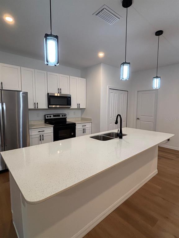 A kitchen features a white quartz island, stainless steel appliances, and white cabinetry — 1204 GOSHEN ROAD, NORTH PORT, FL