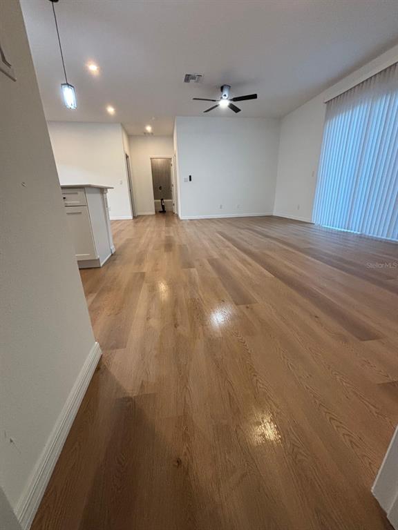A spacious living area features light wood flooring, a ceiling fan, and white walls — 1204 GOSHEN ROAD, NORTH PORT, FL