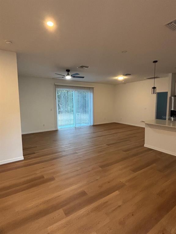 An open-concept living area features light wood-look flooring, a ceiling fan, and sliding glass doors — 1204 GOSHEN ROAD, NORTH PORT, FL