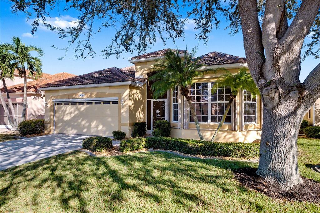 A single-story house with a tan stucco exterior, a tile roof, and a two-car garage — 26268 FEATHERSOUND DRIVE, PUNTA GORDA, FL