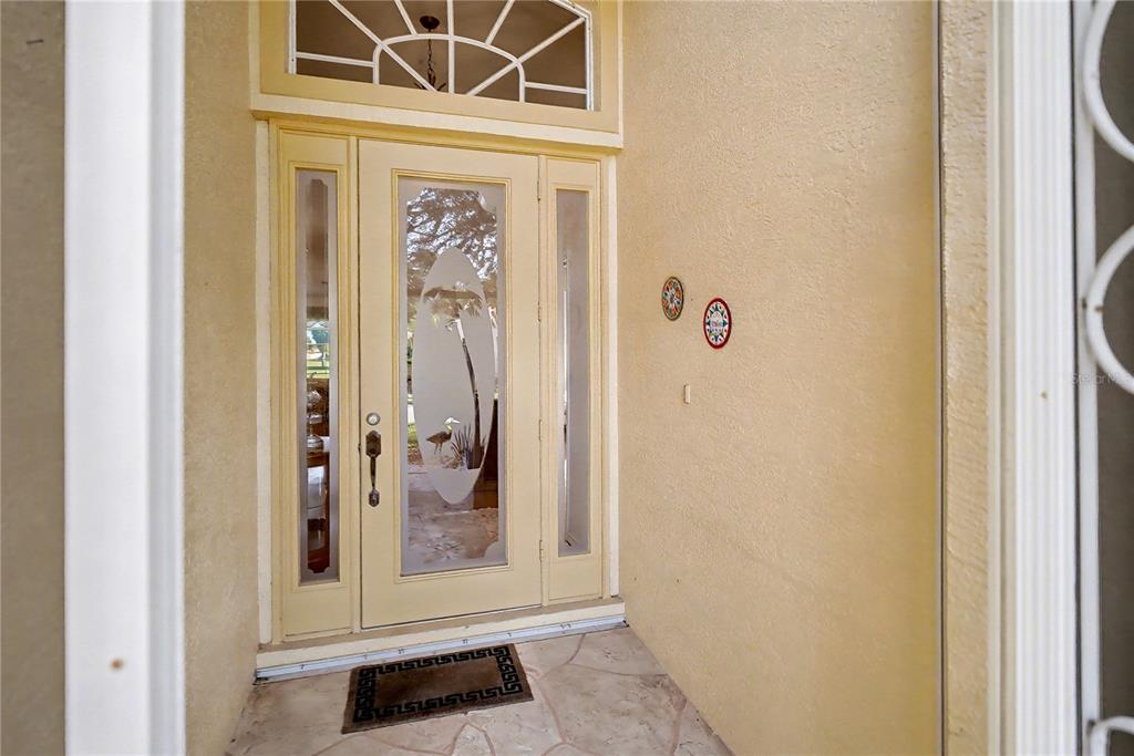 A front entryway features a light yellow door with glass panels and a transom window — 26268 FEATHERSOUND DRIVE, PUNTA GORDA, FL