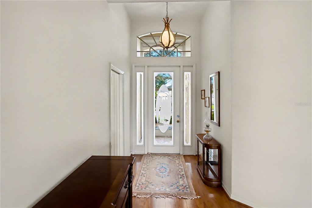 A bright entryway features a wood floor, a patterned rug, and a decorative front door — 26268 FEATHERSOUND DRIVE, PUNTA GORDA, FL