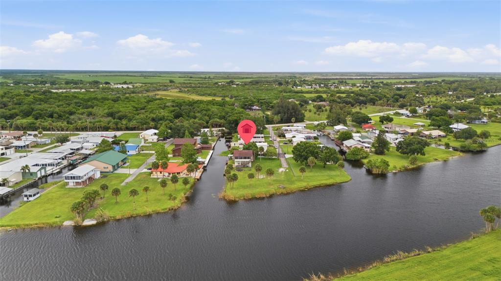 An aerial view shows a waterfront house with a red location pin on a canal — 1056 BLUE HERON LANE, MOORE HAVEN, FL