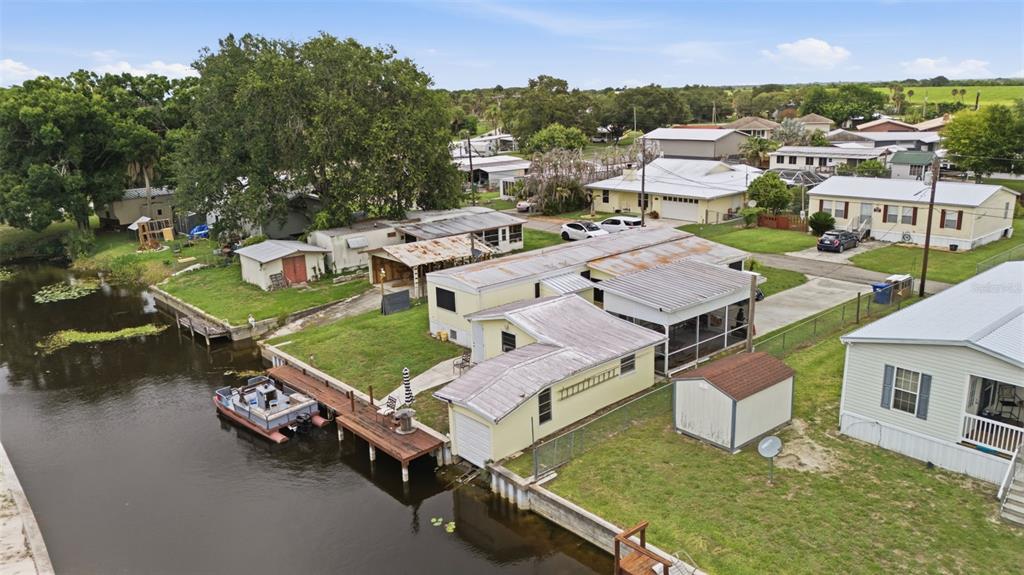 An aerial view shows a waterfront mobile home with a dock, boat, and storage shed — 1056 BLUE HERON LANE, MOORE HAVEN, FL