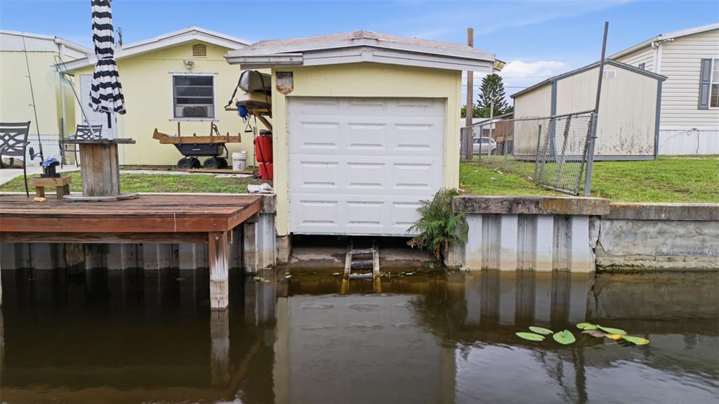 A boat garage with a white door sits on a canal next to a wooden deck — 1056 BLUE HERON LANE, MOORE HAVEN, FL