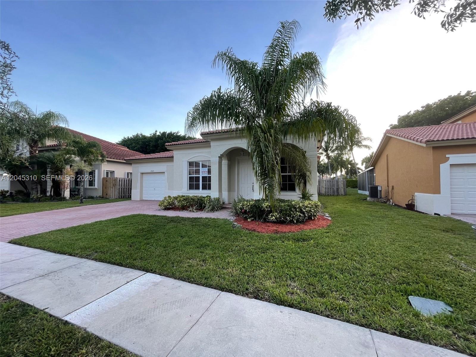 A single-story house with a white stucco exterior, a tiled roof, and a brick driveway — 2008 NE 38th Rd # 2008, Homestead FL 33033, HOMESTEAD, FL