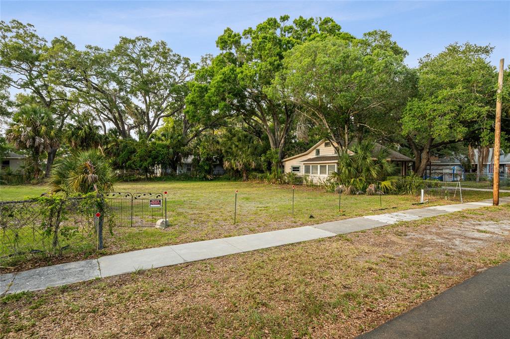 A vacant, grassy lot with a fence and trees sits next to a small house — 1207 34TH STREET, SARASOTA, FL