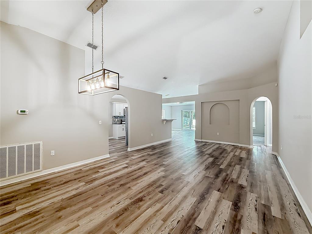 A spacious living area features light gray walls, wood-look flooring, and a rectangular pendant light — 31806 PARKDALE DRIVE, LEESBURG, FL