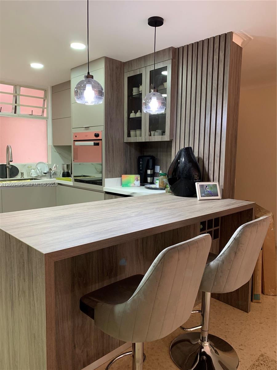 A kitchen features a wood-grain breakfast bar, two upholstered stools, and modern pendant lighting — Carrera 44 17 SUR 70 # 302, AN 050018, AN