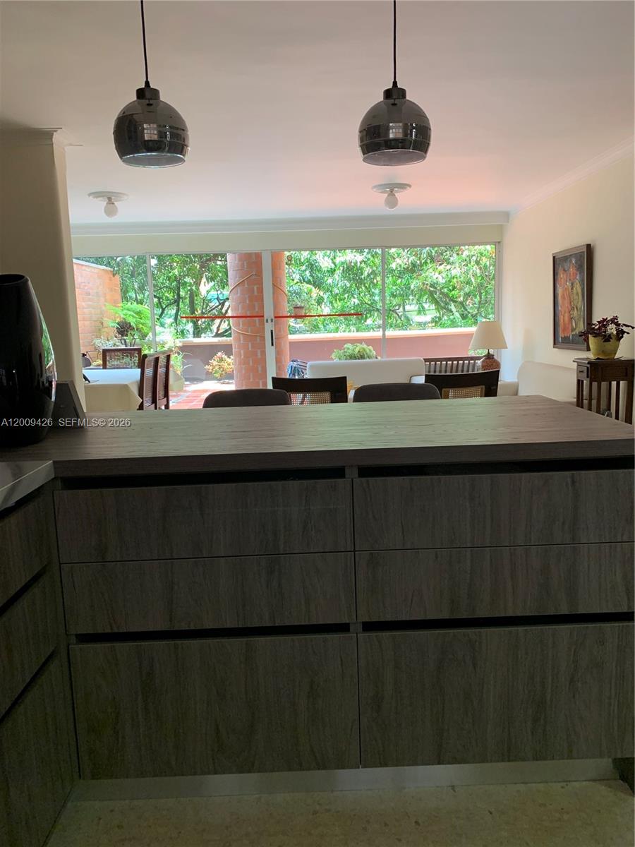 A kitchen island with wood-grain cabinetry faces a dining area with a glass-enclosed balcony — Carrera 44 17 SUR 70 # 302, AN 050018, AN