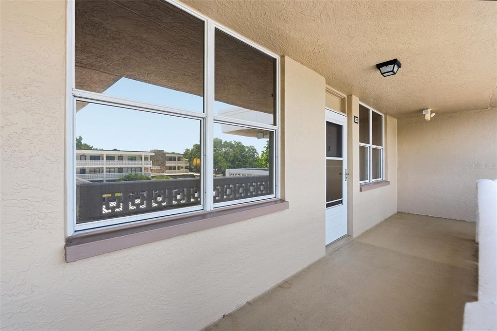 A beige exterior balcony features a white door, large windows, and a concrete floor — 4915 BAY STREET NE UNIT 323, ST PETERSBURG, FL