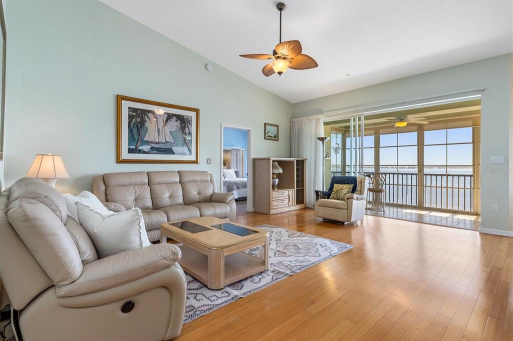 A living room features light wood floors, a beige leather sofa, and a balcony view — 200 HARBOR WALK DRIVE UNIT 354, PUNTA GORDA, FL